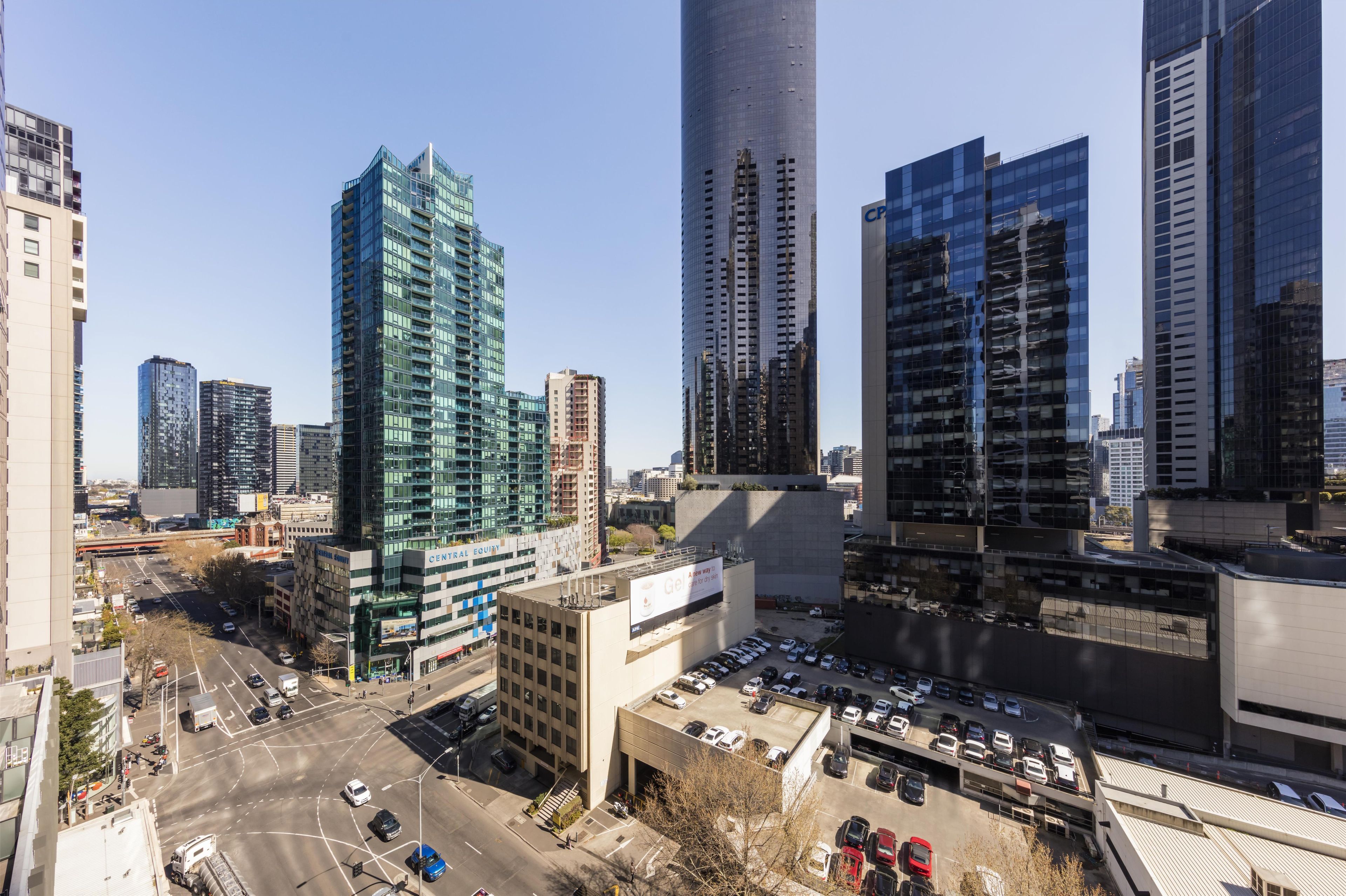 Une vue urbaine avec des immeubles modernes de grande hauteur, un parking et un ciel dégagé.