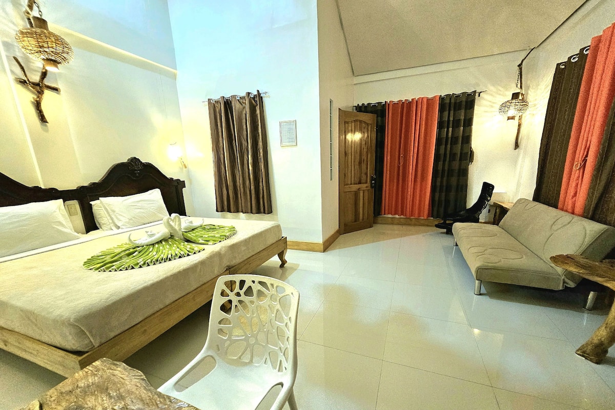 Una habitación de hotel con una cama, un sofá, una silla y una mesa de comedor.