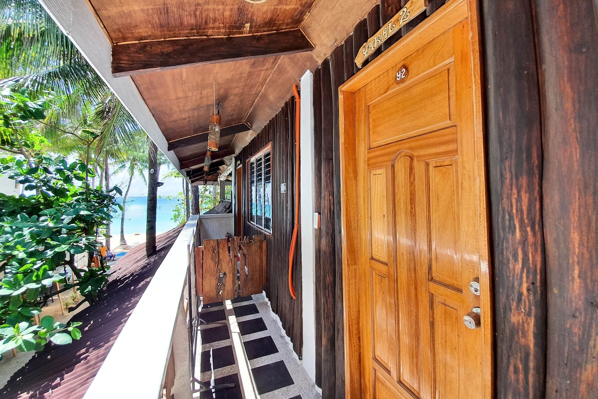 Un pasillo de madera con una puerta de madera que indica “Habitación 2” y una ventana.