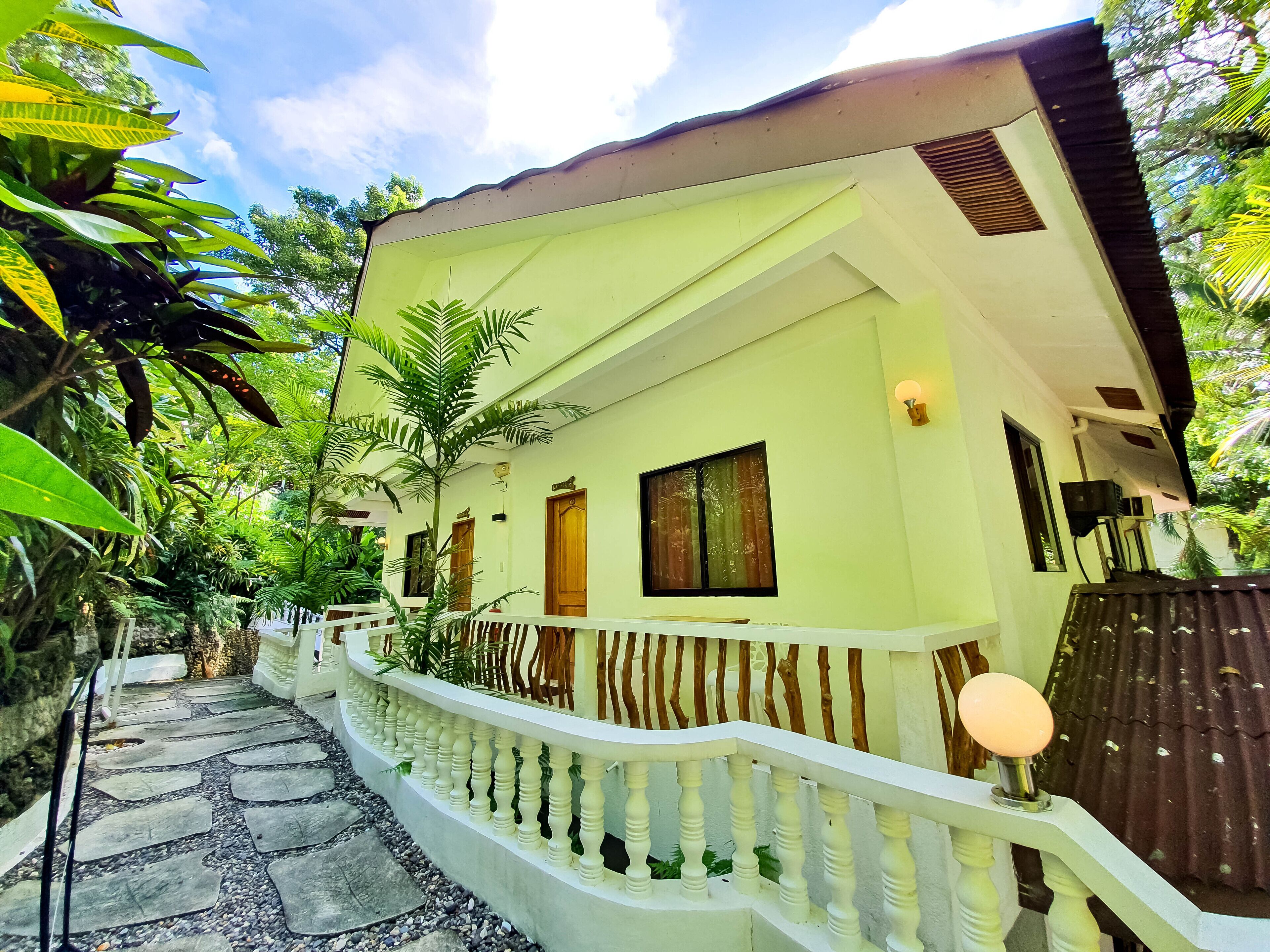 A house with a white exterior, a stone pathway leading to the entrance, and a white railing along the pathway.