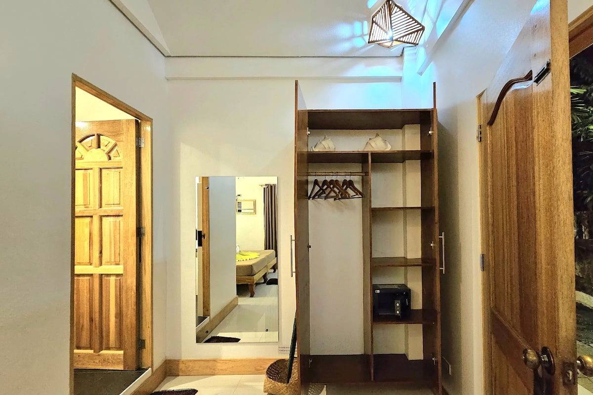 Un pasillo con puerta de madera, un espejo, un armario y una percha.