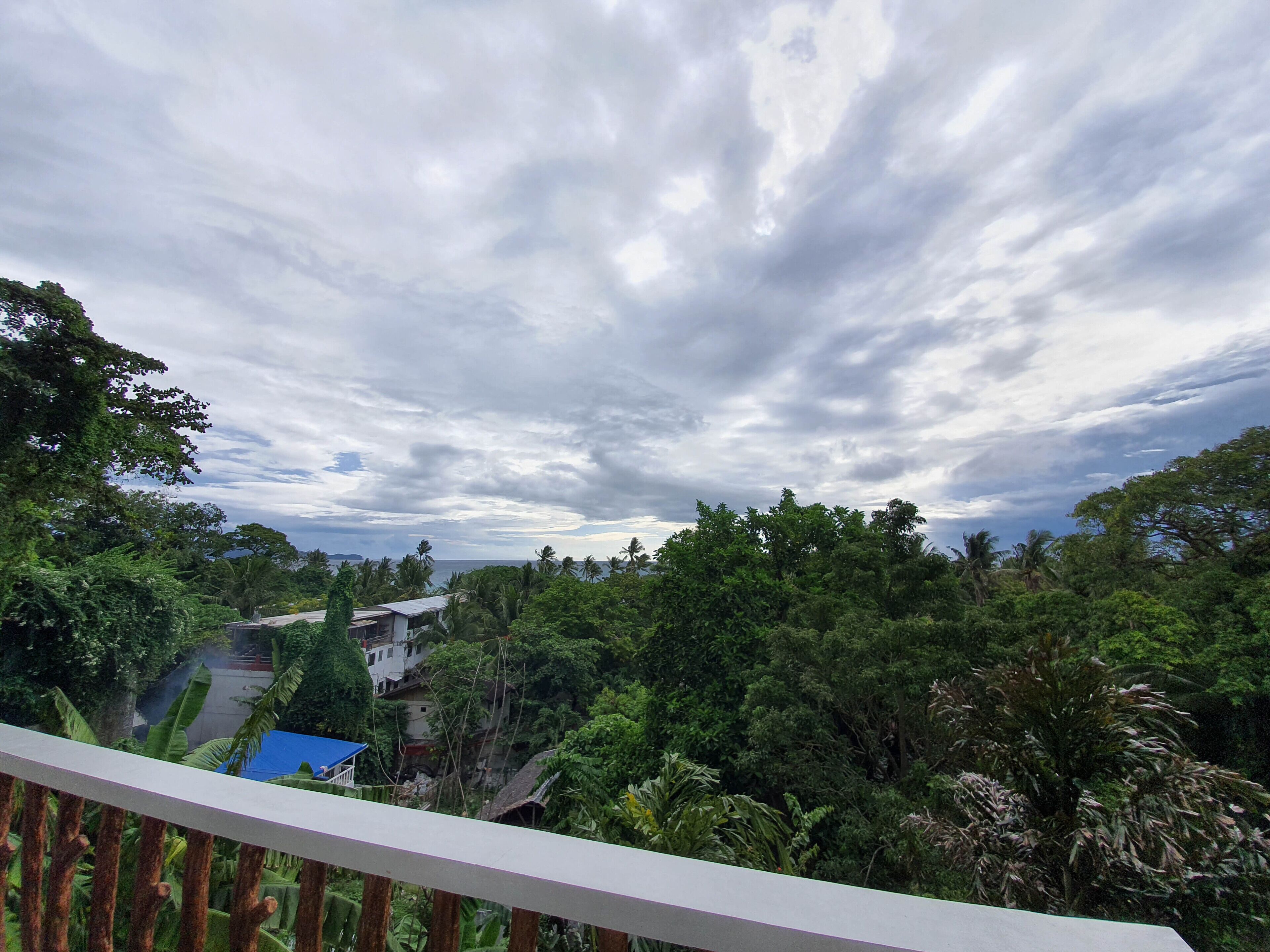 Un balcón con vistas a un paisaje verde exuberante y un cielo nublado.