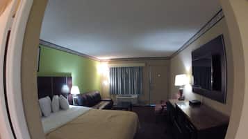 Een hotelkamer met een bed, een bureau, een stoel, een televisie en een raam met gordijnen.