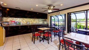 A restaurant with a kitchen area, dining tables with chairs, and a view of the outdoors. - Budget Host Inn (Florida City)