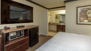 A hotel room with a bed, a built-in microwave, a small refrigerator, a vanity with a mirror, and a framed picture on the wall. - Budget Host Inn (Florida City)