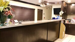 A kitchen with a dark countertop, a ceiling fan, and a refrigerator. - Budget Host Inn (Florida City)