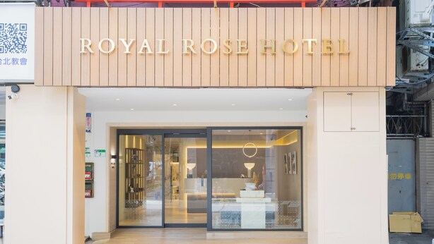 Exterior del Hotel Royal Rose, con fachada de madera y un amplio acceso de vidrio.