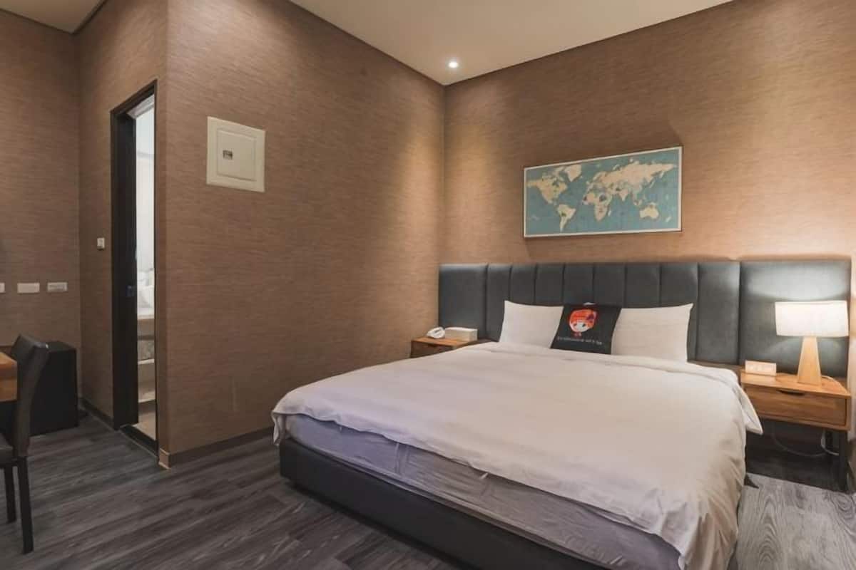 Une chambre d’hôtel avec un grand lit, une tête de lit, une table de chevet, un bureau et une chaise.
