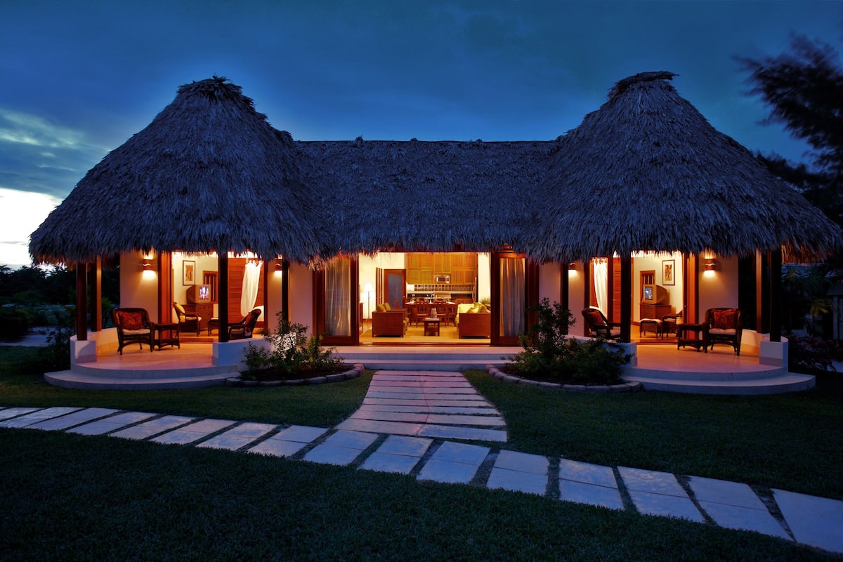 A thatched-roof building with a central open area and two side patios, each with seating.