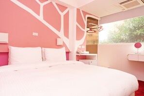 Un dormitorio con una cama grande, un escritorio y una ventana con vistas a zonas verdes.