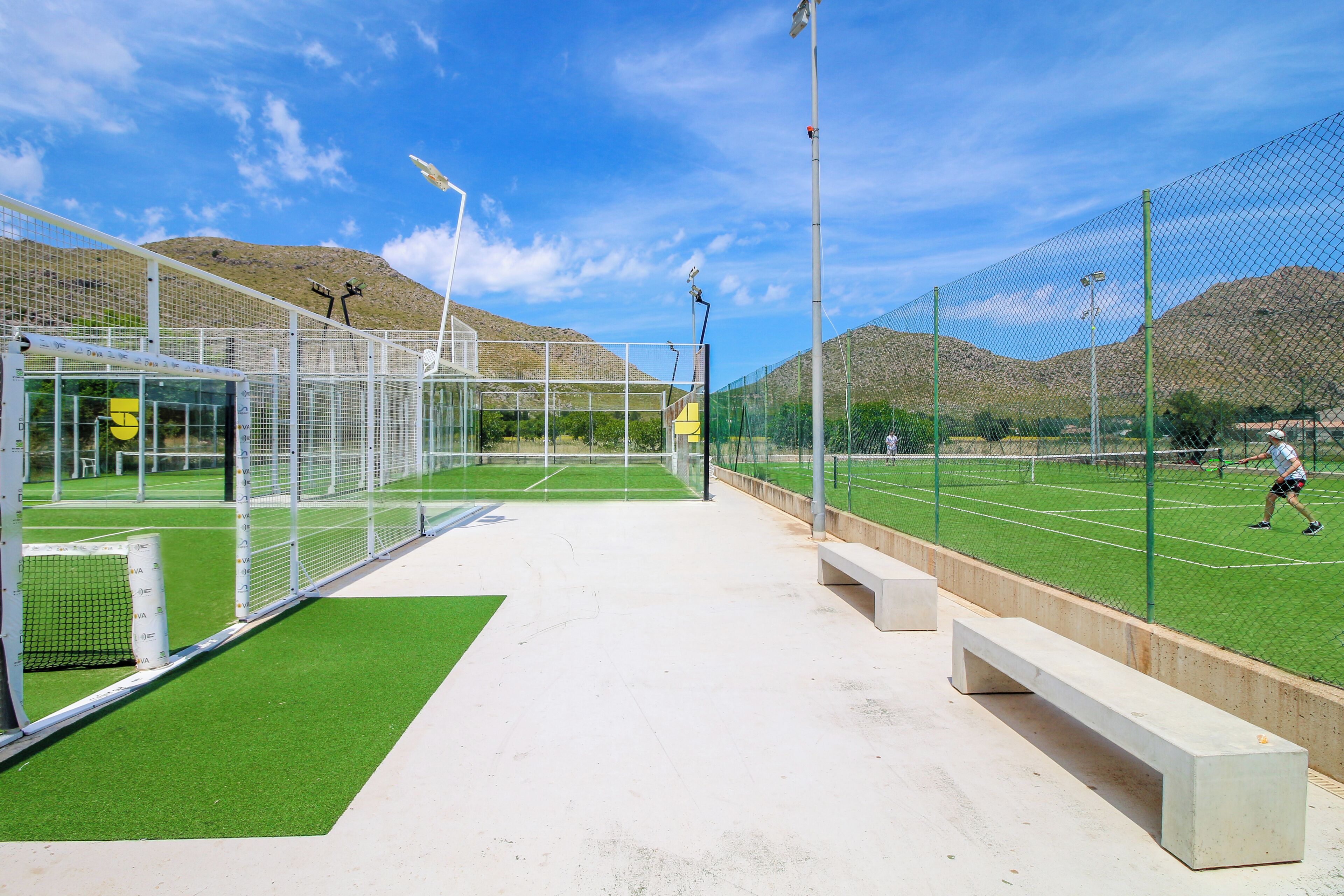 An indoor tennis court with a net, benches, and a goalpost.