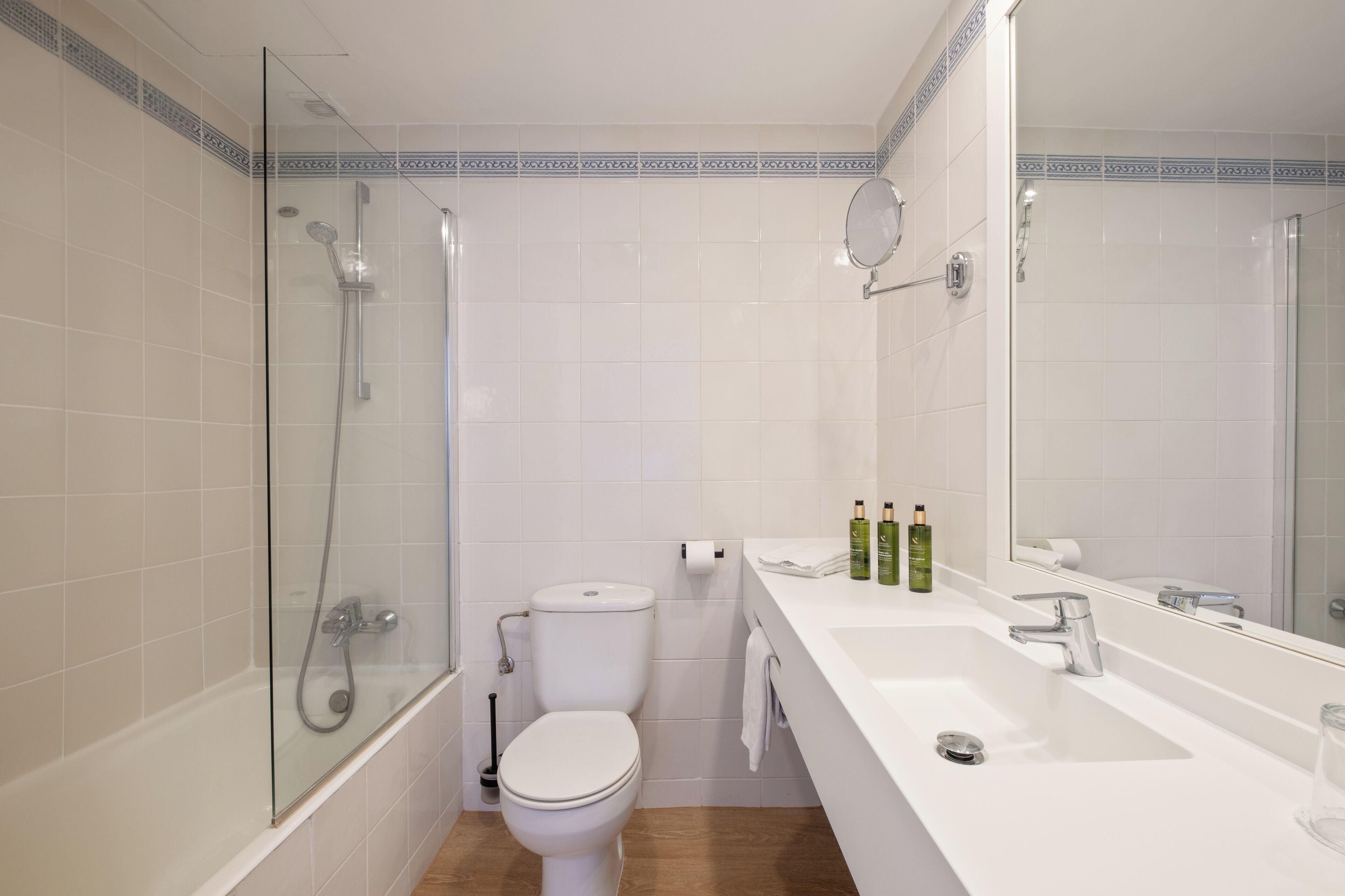 A bathroom with a glass-enclosed shower, a toilet, a sink, and a mirror.