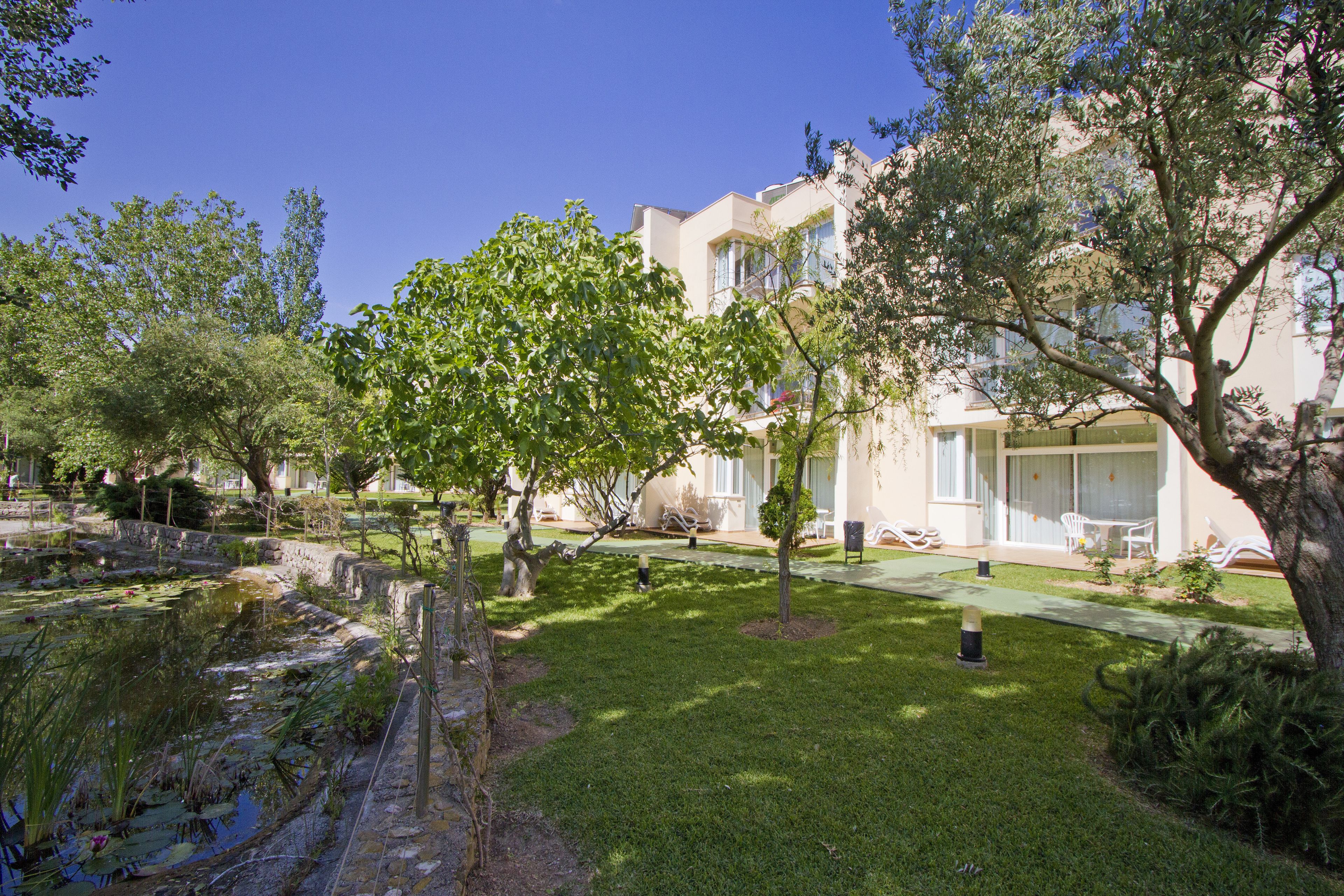 A building with a garden, a pond, and outdoor seating.
