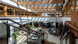 Un intérieur spacieux avec de hauts plafonds, des poutres en bois et de grandes fenêtres qui laissent entrer la lumière naturelle.