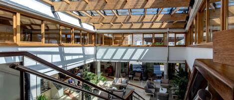 A spacious interior with a high ceiling, wooden beams, and large windows allowing natural light.