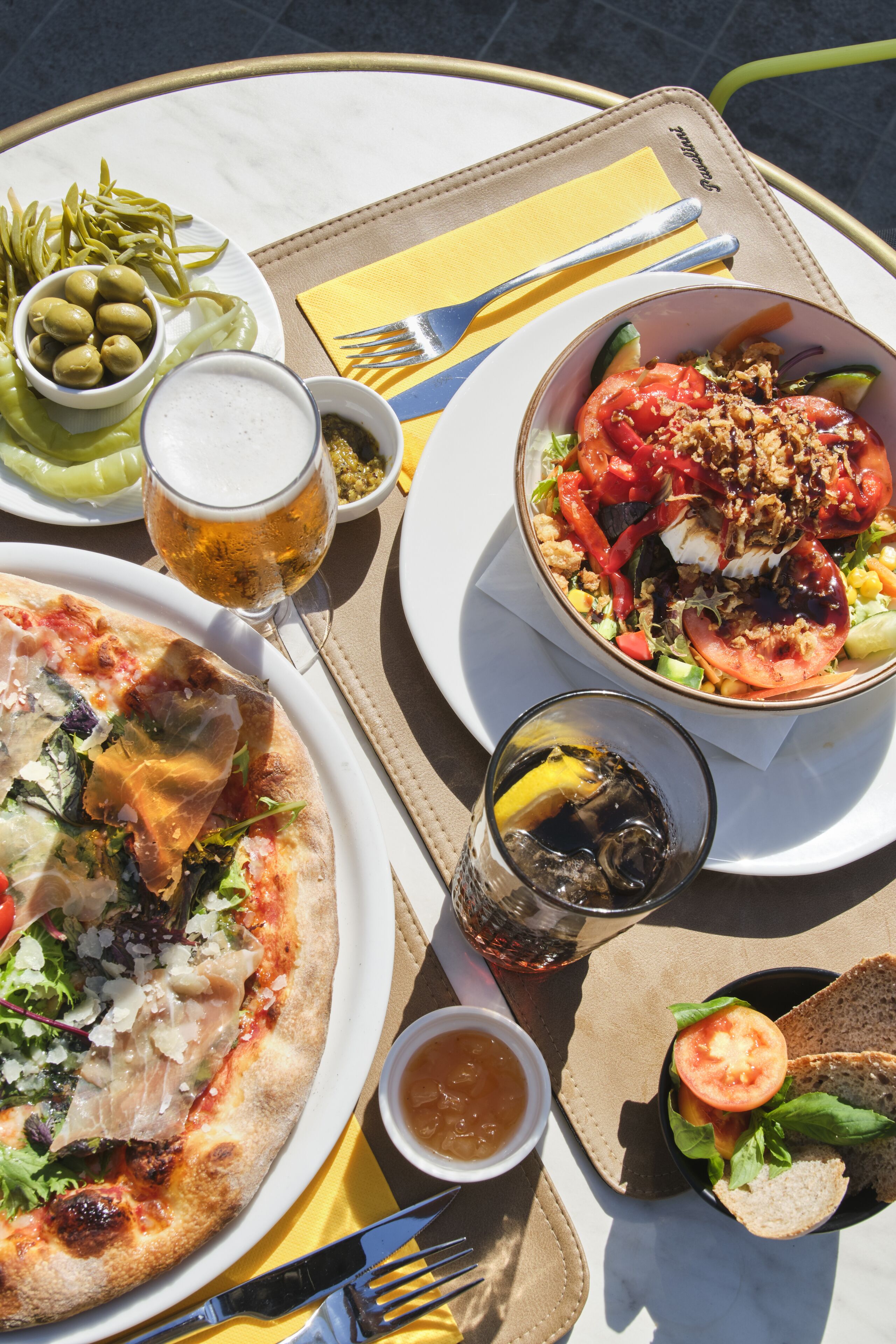 Una mesa con pizza, ensalada y bebidas.