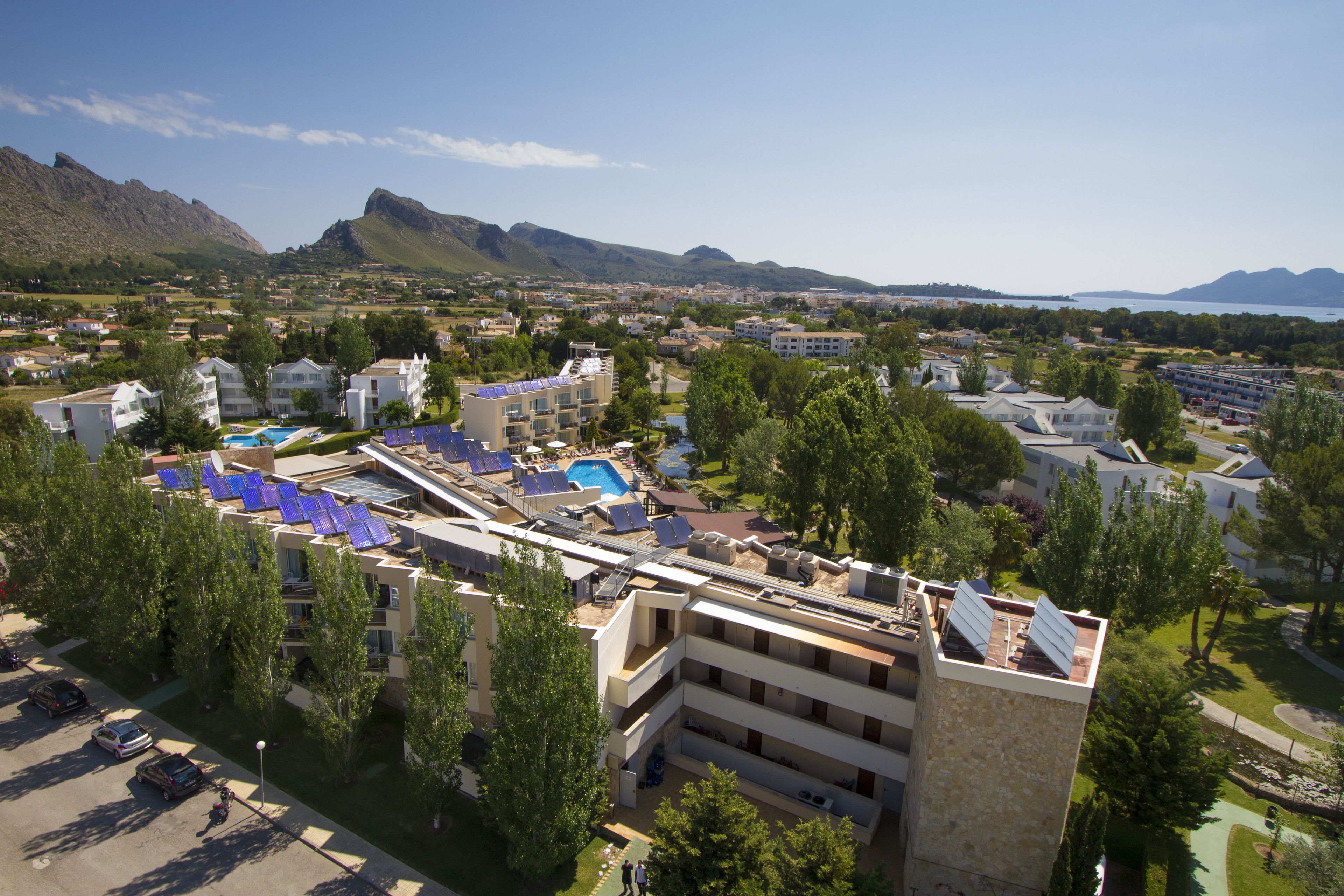 A hotel with multiple floors, a rooftop pool, and a view of mountains in the background.