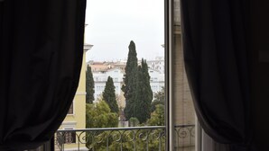 A view from a balcony with curtains, overlooking a row of buildings and tall trees. - Residenza dei Quiriti (Rome)