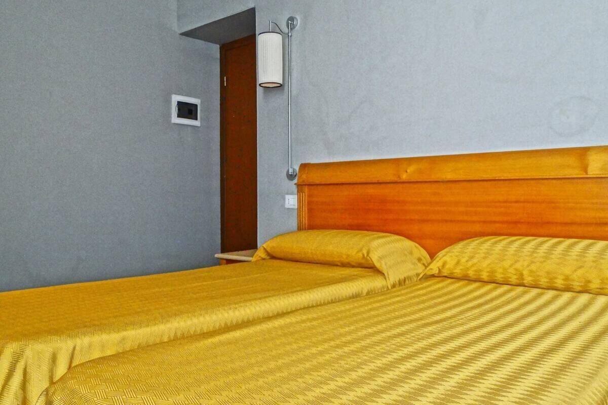 A room with a bed, a wall-mounted light, and a door.