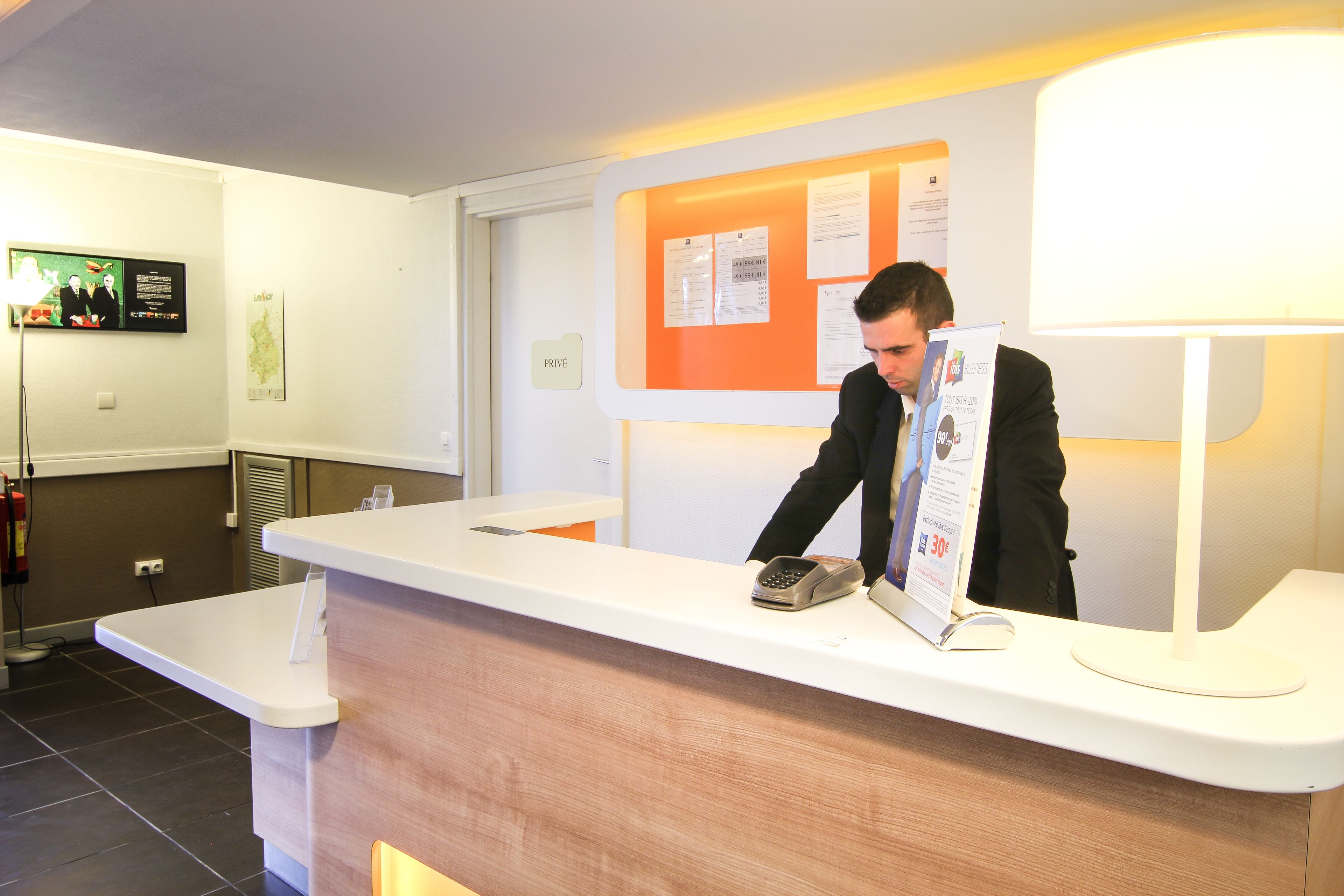 A reception desk with a telephone, a bulletin board with papers, and a "PRIVÉ" sign.