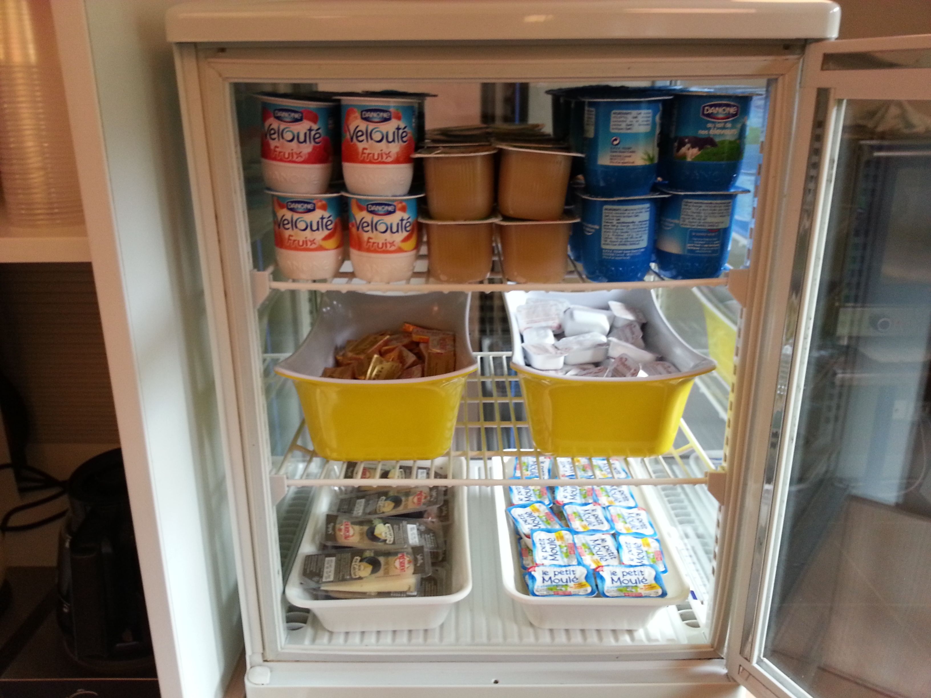 Ein Kühlschrank, gefüllt mit verschiedenen Lebensmitteln, darunter Konserven, Joghurt und verpackten Produkten.
