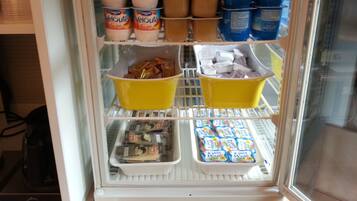 Ein Kühlschrank, gefüllt mit verschiedenen Lebensmitteln, darunter Konserven, Joghurt und verpackten Produkten.