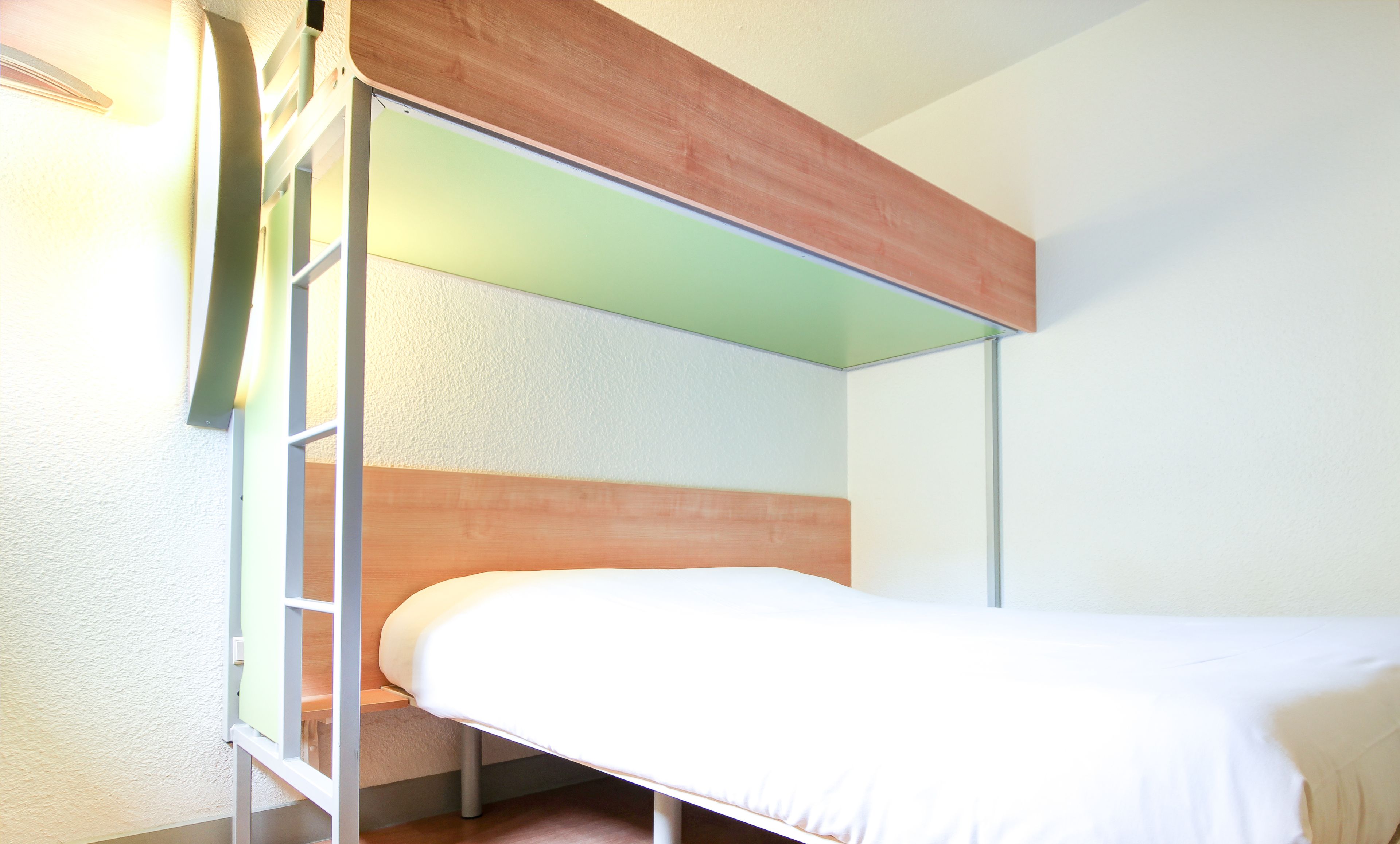 Ein Stockbett mit Holzkopfstück und weißer Matratze.