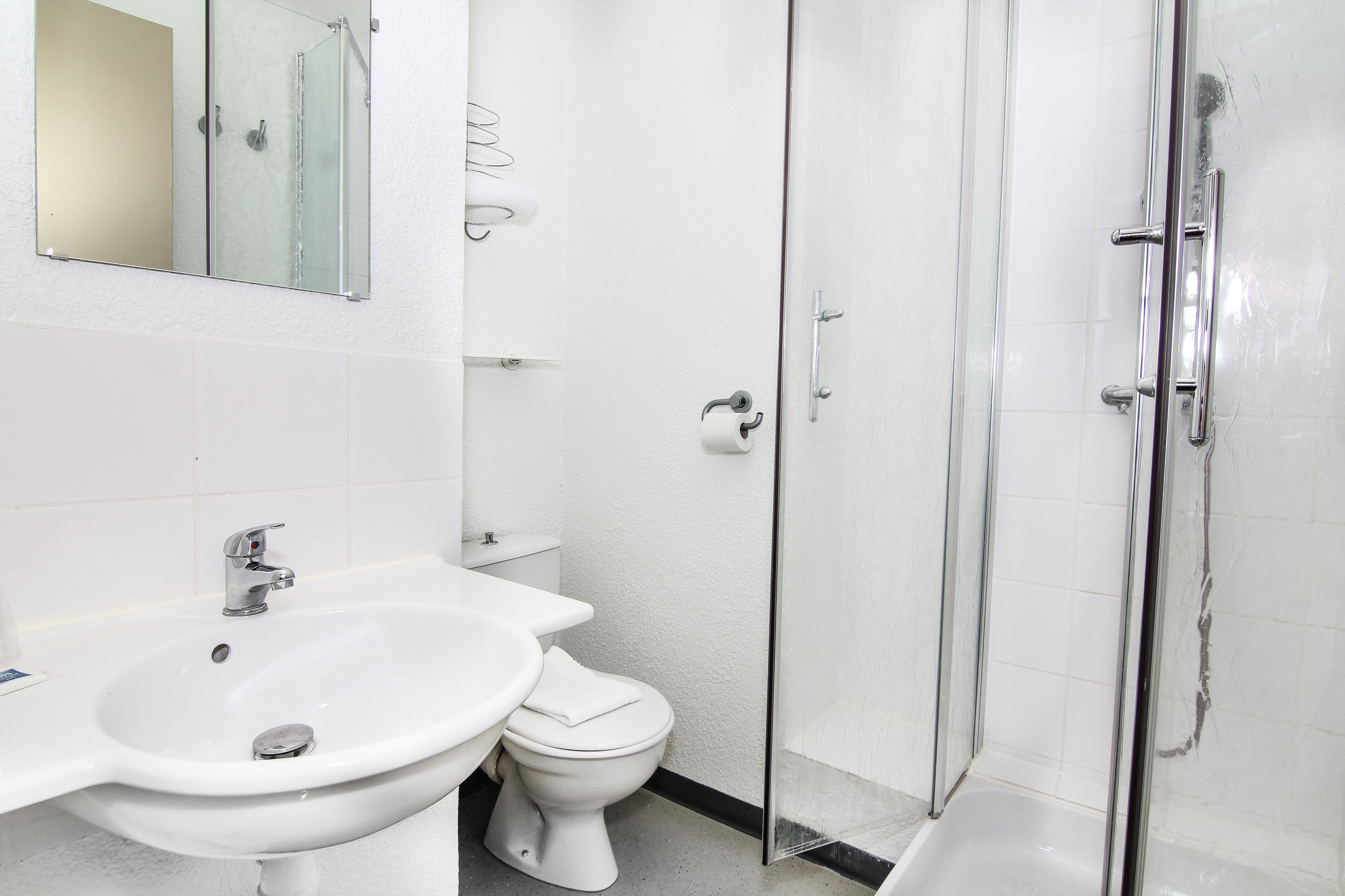 A bathroom with a sink, toilet, and glass shower enclosure.