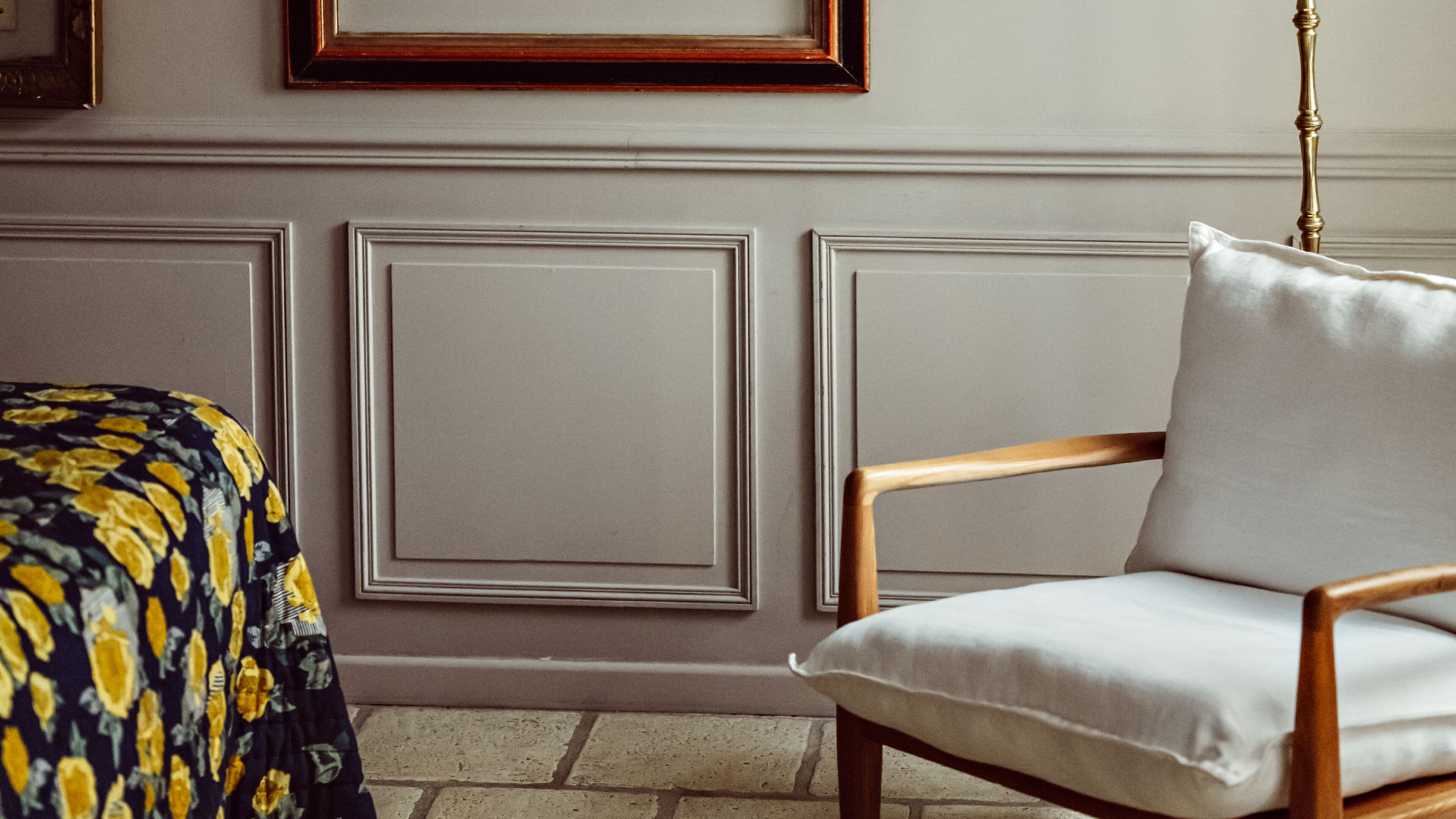 Une pièce comprenant un lit, une chaise et un mur orné de moulures décoratives.