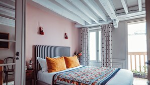 Une chambre à coucher avec un lit, une table de chevet, une chaise et une fenêtre avec des rideaux.