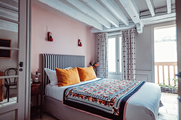 A bedroom with a bed, a nightstand, a chair, and a window with curtains. - Hotel Maison Saintonge (Paris)