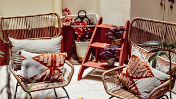 Wicker chairs with cushions, a red chair, and a small table with decorative items.
