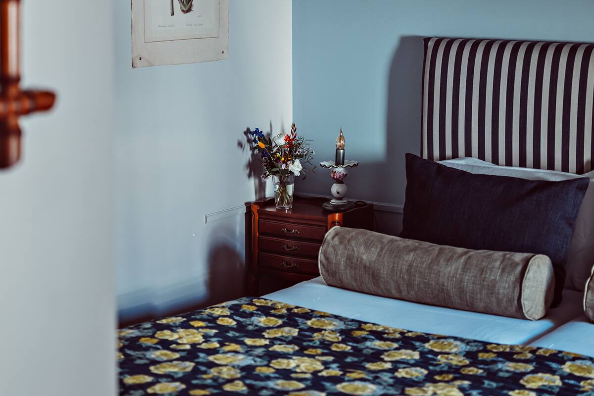 Une chambre à coucher avec un lit, une table de chevet, une commode, une lampe et un tableau encadré au mur.