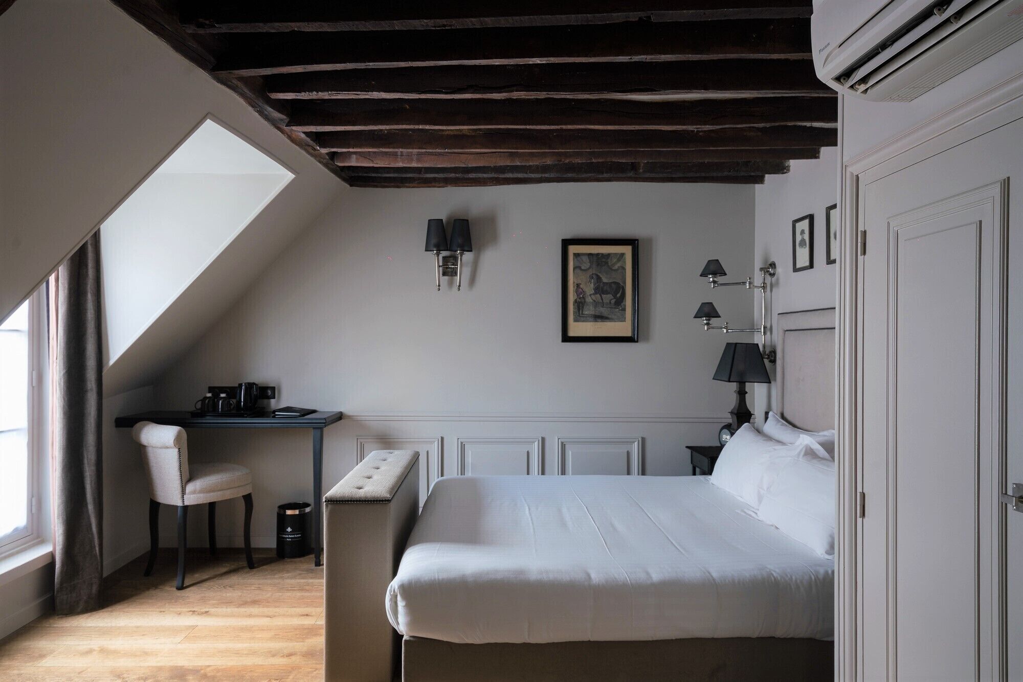 A bedroom with a large bed, a desk, a chair, and a window.