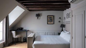 A bedroom with a large bed, a desk, a chair, and a window.