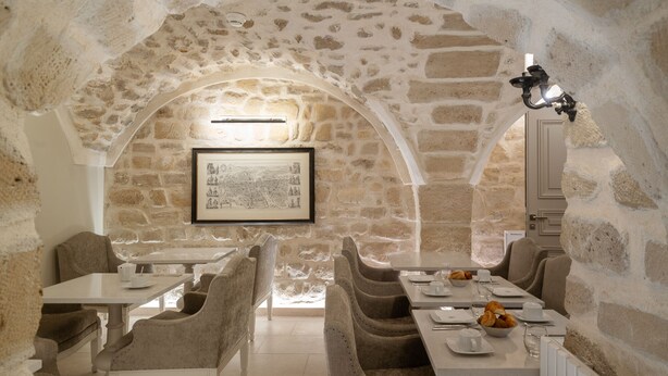 A stone-walled dining area with a high arched ceiling, framed artwork on the wall, and a table set for a meal. - Hotel Saint-Louis en L'Isle - Notre-Dame (Paris)