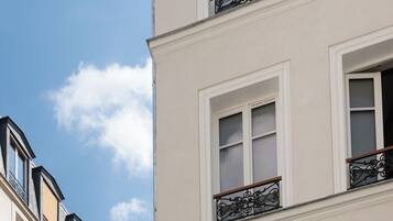 Un immeuble à plusieurs étages, doté de façades blanches et de balcons en fer forgé noir.