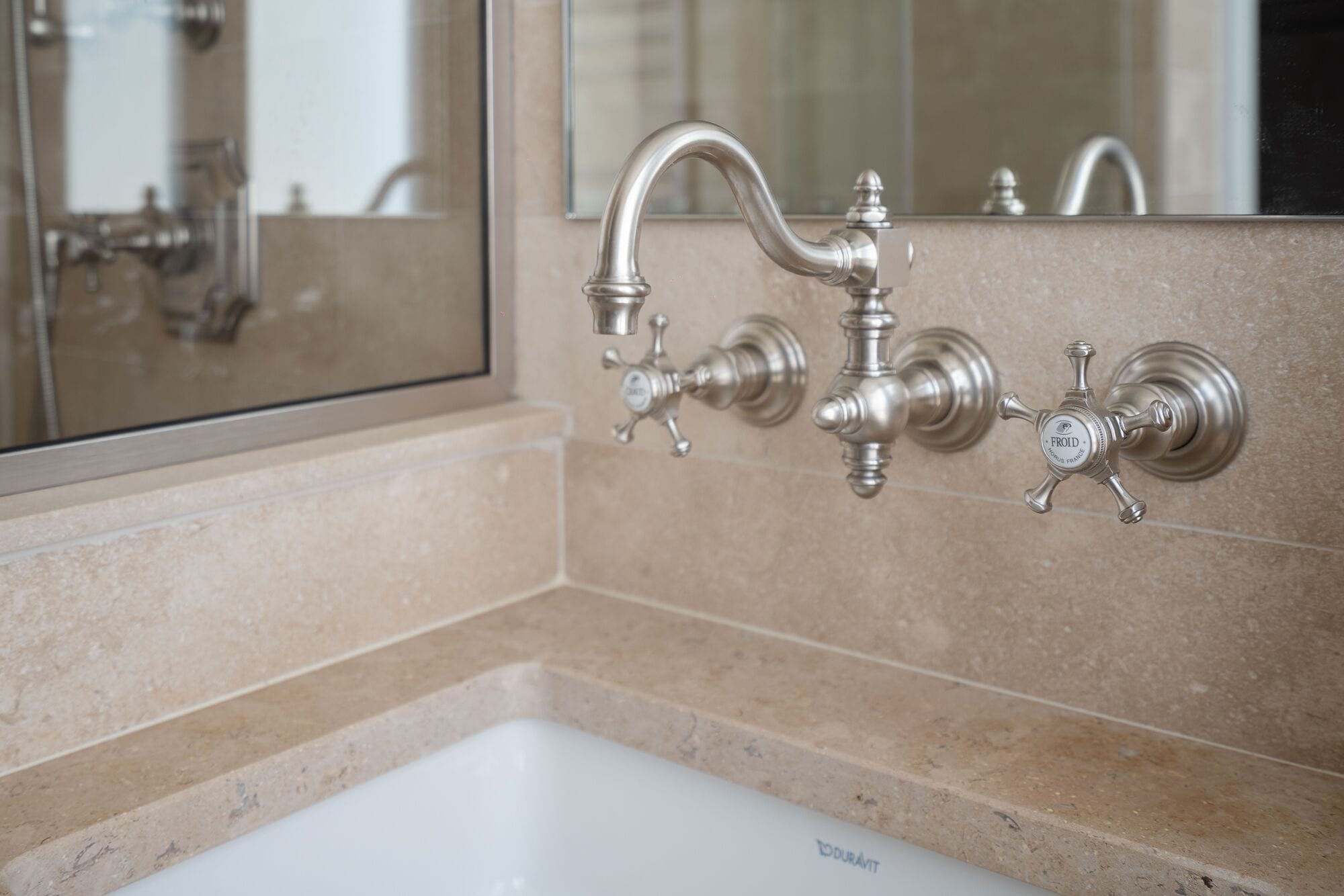 Un baño con lavamanos blanco, un grifo curvo y un espejo que refleja el baño.
