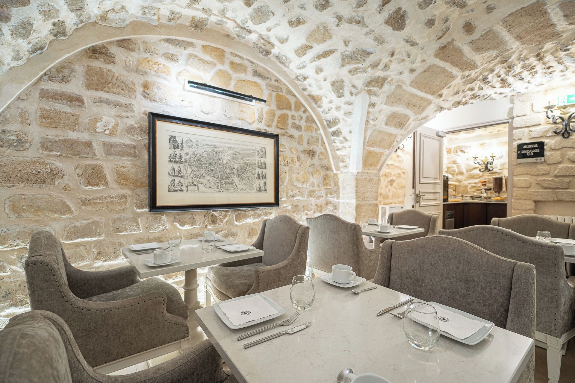 A restaurant with stone walls, framed historical map, and modern dining setup.
