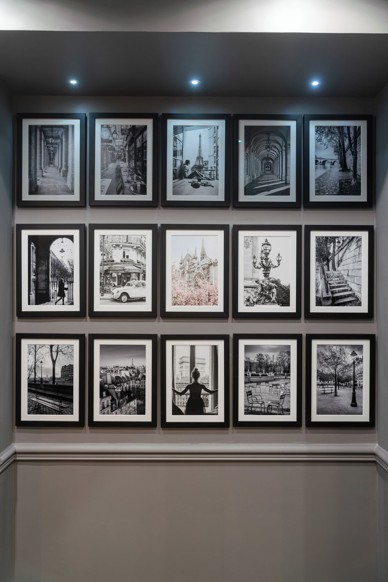 A gallery of black and white photographs on a wall, each framed and evenly spaced.