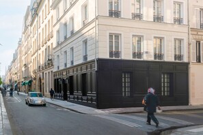 A street view of a building with a black facade and large windows.