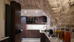 A modern kitchen with dark wood cabinets, a central island with a sink, and a stone archway. - Hotel Saint-Louis en L'Isle - Notre-Dame (Paris)