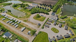 An aerial view of a campground with RV parking, buildings, and a lake. - Storkesøen Ribe (Ribe)