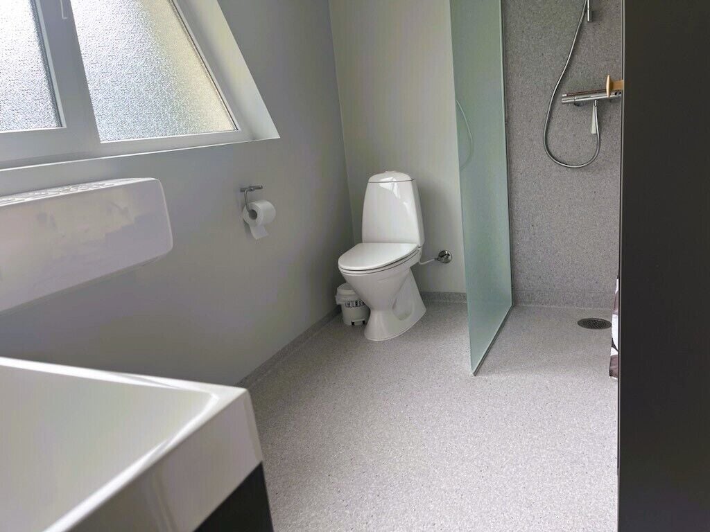 Et badeværelse med toilet, bruser og et vindue.