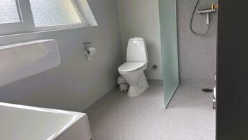 Et badeværelse med toilet, bruser og et vindue.