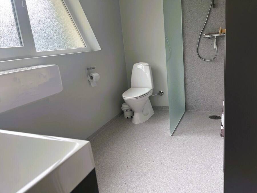 Et badeværelse med toilet, bruser og et vindue.