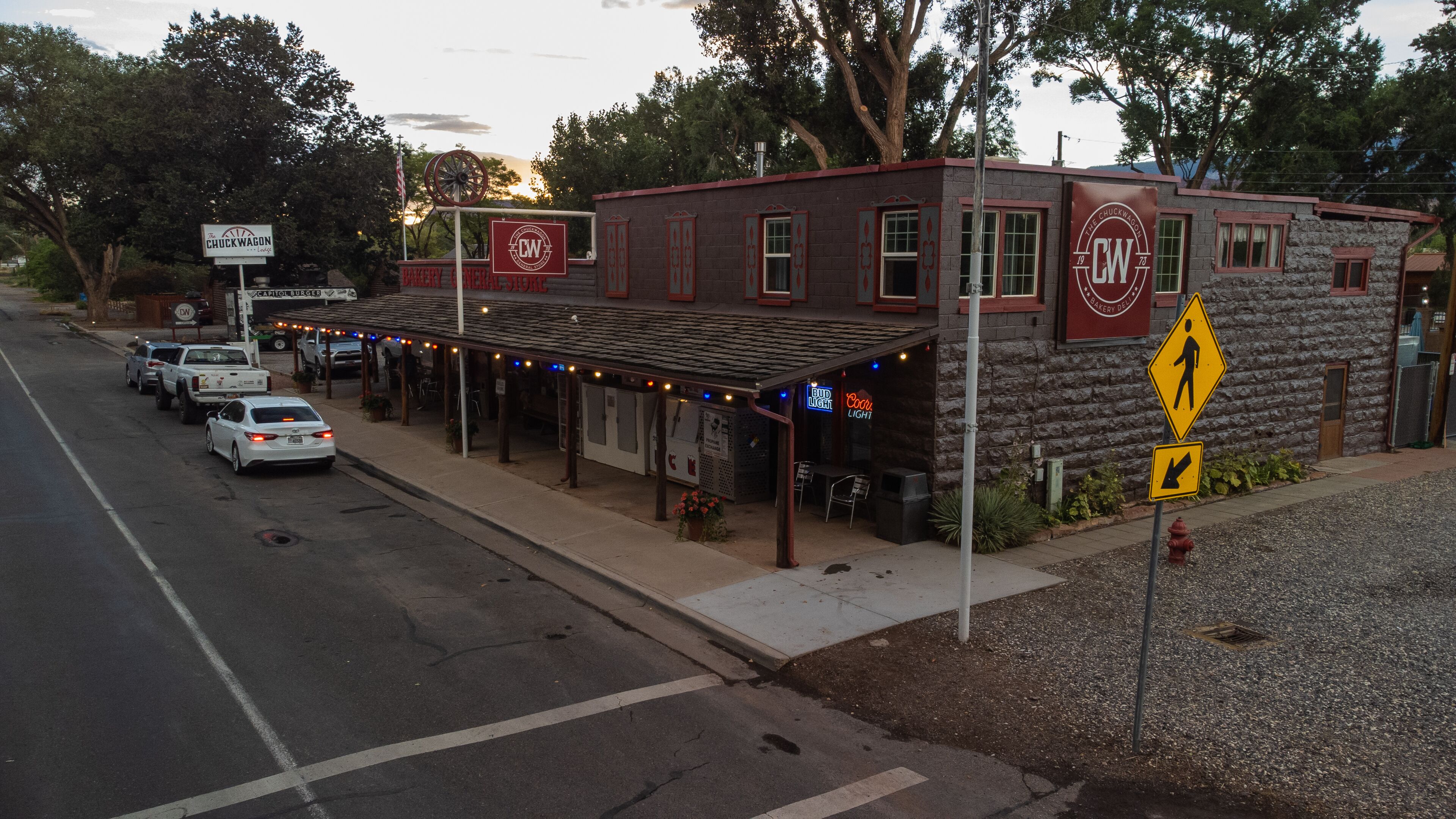 A building with a sign reading "The Chuckwagon" and "Bakery General Store." There are cars parked in front, and a pedestrian crossing sign is visible.