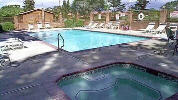 En sÀsongsöppen utomhuspool, parasoller och solstolar