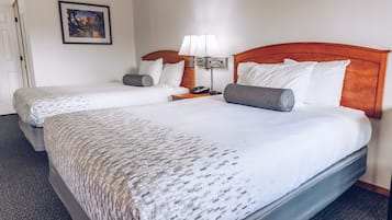 A hotel room with two beds, a nightstand with a lamp, and a framed picture on the wall.