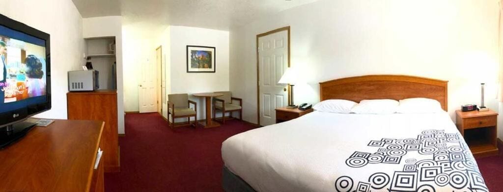 Una habitación de hotel con cama, escritorio, televisor y puerta.